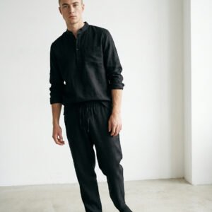 Vīriešu brīva piegriezuma lina tunika maigi, dabīgi melnā krāsā ar minimālisma dizainu ar garām piedurknēm un šķēlumiem sānos, neformālā stilā pāri biksēm, lai radītu relaksējošu, elpojošu izskatu.