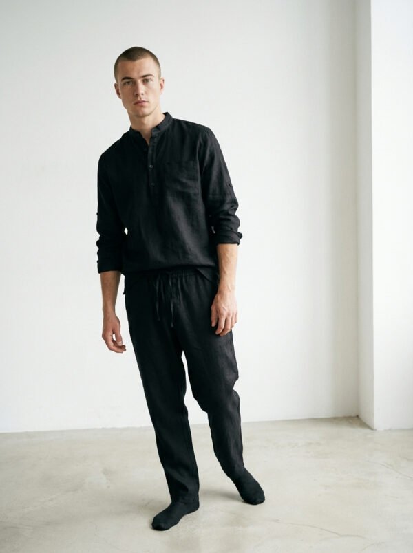 Vīriešu brīva piegriezuma lina tunika maigi, dabīgi melnā krāsā ar minimālisma dizainu ar garām piedurknēm un šķēlumiem sānos, neformālā stilā pāri biksēm, lai radītu relaksējošu, elpojošu izskatu.