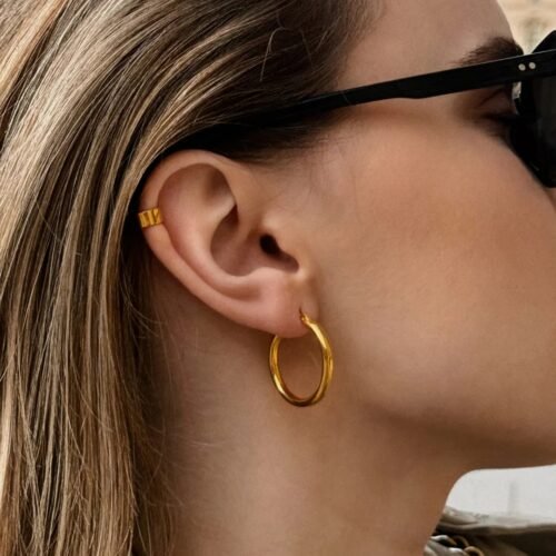 django-hoops-gold-950afd9f.jpg Gold hoop earrings with a minimalist design, featuring a smooth polished finish and a timeless circular shape, elegant and versatile for everyday wear.