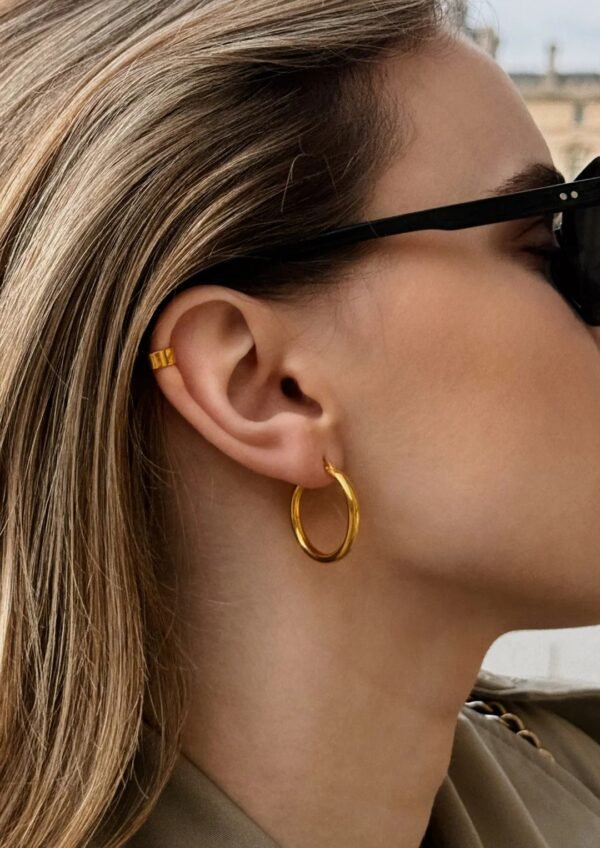 Gold hoop earrings with a minimalist design, featuring a smooth polished finish and a timeless circular shape, elegant and versatile for everyday wear.