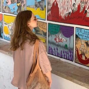 Person observing colorful wall murals witg bag